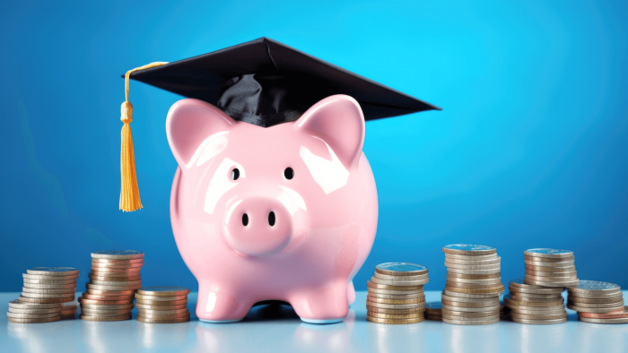 piggy bank wearing graduation cap next to stacks of coins