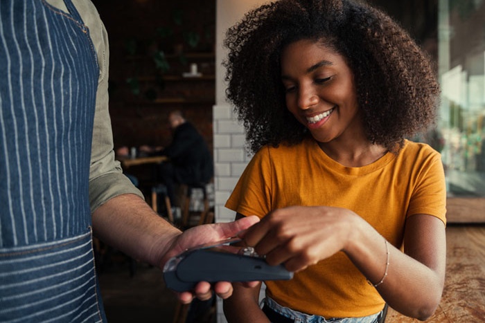 Young woman using debit card at cafe