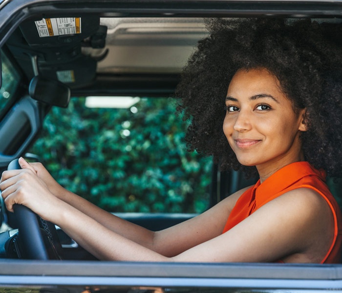 Woman in driver's seat of a car with hands on the wheel