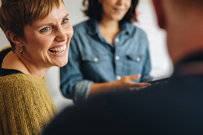 Woman smiling at man during a group meeting.