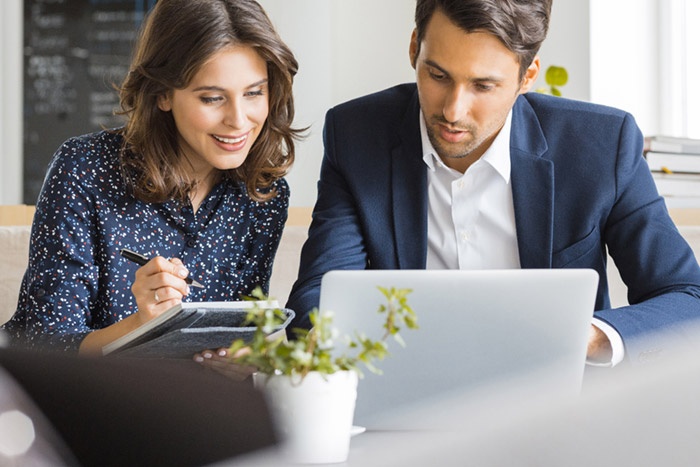 Corporate man and woman looking at laptop and taking notes