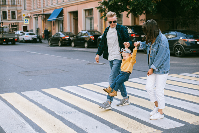 Parents swinging child on crosswalk